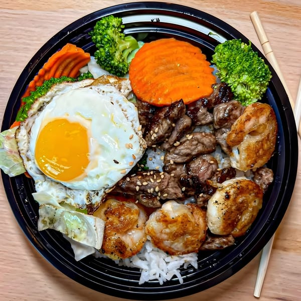 Tokyo Teriyaki bowl with beef, shrimp, fried egg, broccoli, carrots, and rice, with chopsticks.