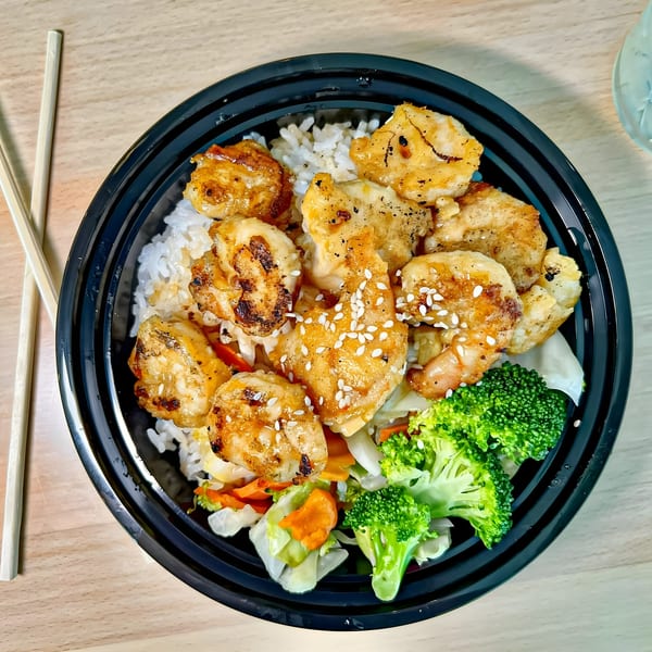 Tokyo Teriyaki chicken and rice bowl with broccoli, carrots, and sesame seeds, with chopsticks.