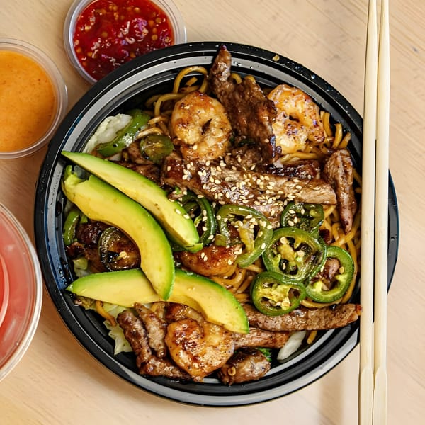 Tokyo Teriyaki bowl with noodles, beef, shrimp, avocado, jalapeños, and sesame seeds, with sauces and chopsticks.
